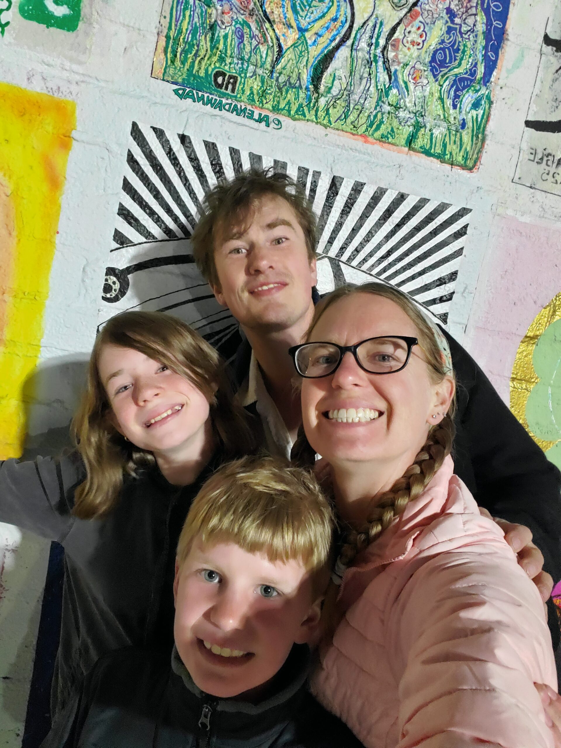 A picture of the Donaldson family in front of a colorful painting background. Dad, Mom, Son and Daughter are all smiling.